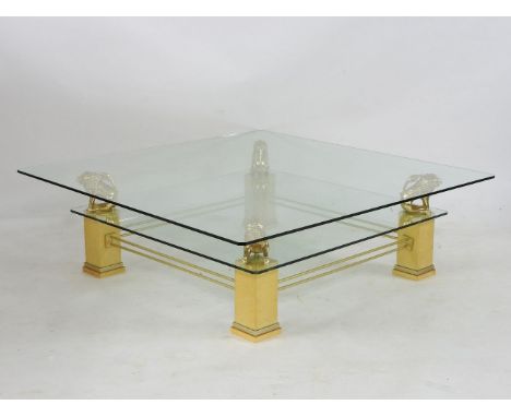 A modern square coffee table, the glass top on four gilt lion supports, lower glass shelf and short square legs, 136cm square