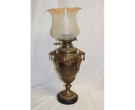 An ornate old brass pedestal oil lamp with detachable font and amber-tinted opaque glass shade