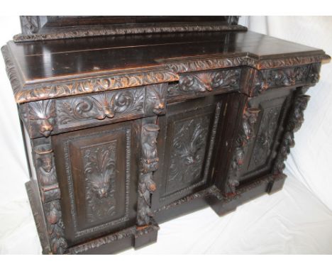 A 19th century heavily carved oak break-front sideboard with three-drawers in the frieze and a cupboard enclosed by three hea