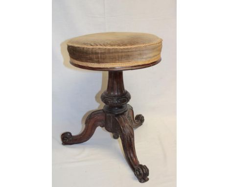 A Victorian carved mahogany piano stool with upholstered circular revolving seat on scroll legs