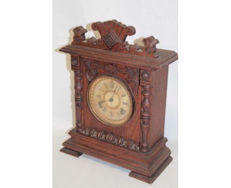 An old Continental mantel clock with decorated circular dial in stained pine carved case