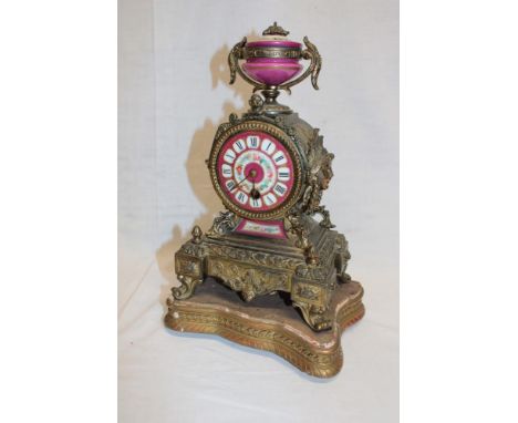 A French brass mantel clock with porcelain circular dial in relief decorated tapered case 11" high on gilt stand