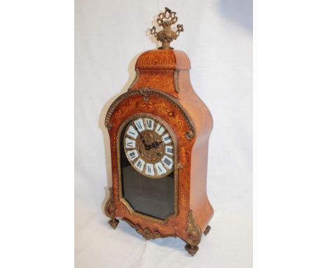 An ornate French mantel clock with brass circular dial and individual porcelain numerals in walnut brass mounted arched case 