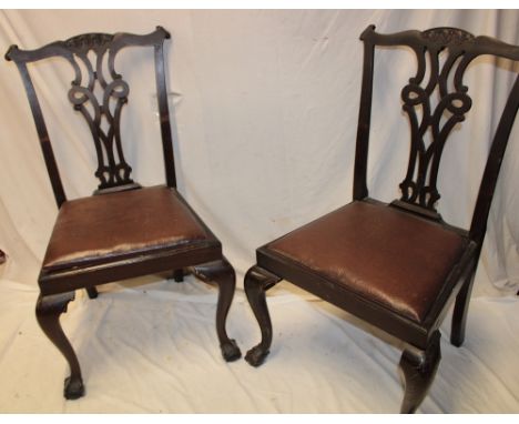 A set of four mahogany Chippendale-style dining chairs with pierced vase splat backs and leather upholstered seats on cabriol