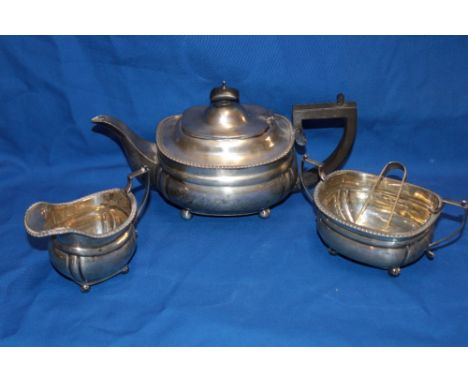 An Edward VII silver three-piece tea set comprising an oval tea pot with hinged lid and ebonised handle, matching milk jug an