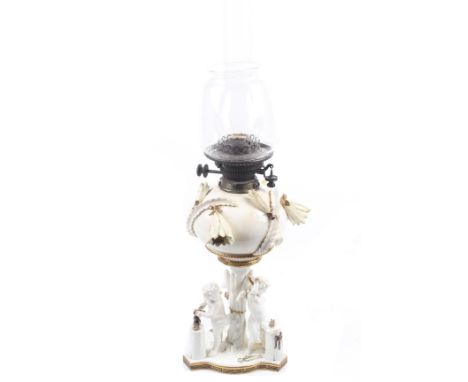 A Victorian Moore ceramic oil lamp. Having a trefoil base with three cherubs below the reservoir with applied flowering cactu