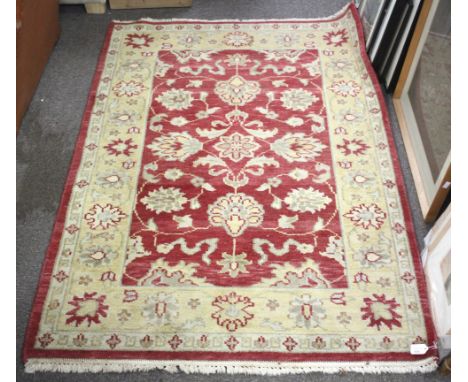 A vintage red and cream ground wool rug. Multi border with red ground central medallion with floral decoration. 180cm x 117cm