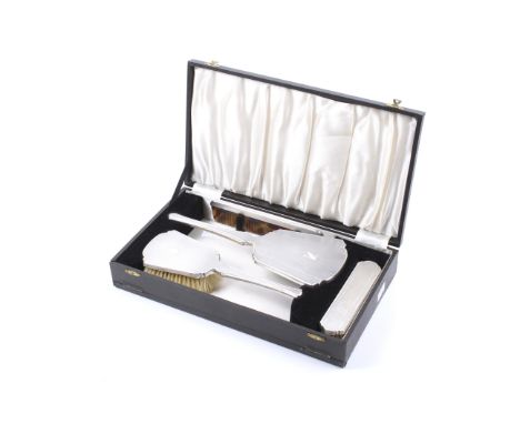 A silver mounted four piece dressing table set. Comprising; a tapering rectangular hand mirror, a hair brush, a clothes brush
