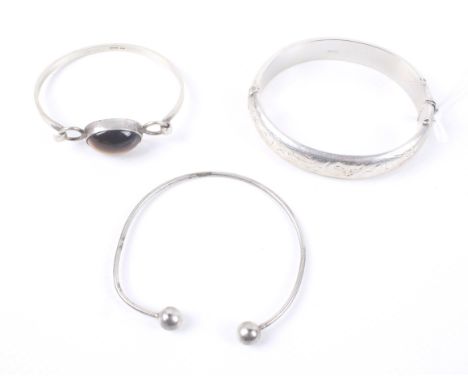 Two vintage silver bangles and a silver-plated torque bangle. Comprising; a part foliate engraved hollow hinged bangle, hallm