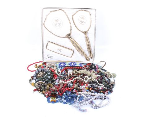 An assortment of vintage costume jewellery and a boxed dressing table set. The jewellery including a gold plated necklace, a 
