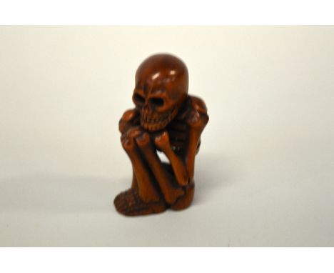 A JAPANESE BOXWOOD NETSUKE, study of a skeleton, signed to the base