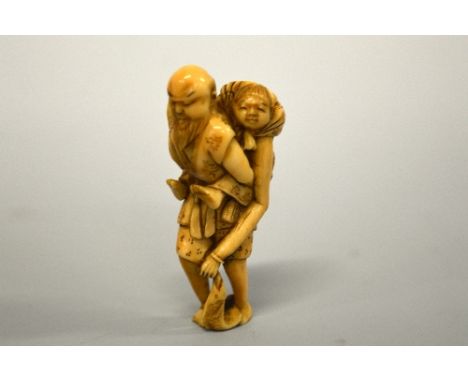 A JAPANESE IVORY NETSUKE, figure of an old man carrying an old lady who is holding a fish