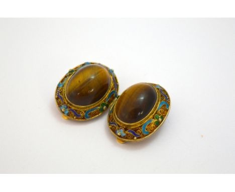 A PAIR OF ENAMELLED FILIGREE TIGERS EYE CLIP EARRINGS, with central oval cabochon tigers eye within a scrolling enamel surrou