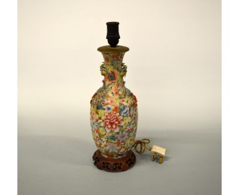 AN ORIENTAL HAND PAINTED FLORAL DECORATED LAMP, on hardwood carved stand, with birds in relief to neck, drilled for electrici
