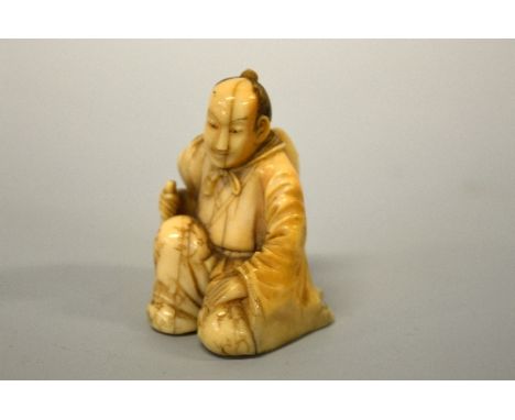 A JAPANESE IVORY NETSUKE, figure of a man kneeling with an axe, signed to base