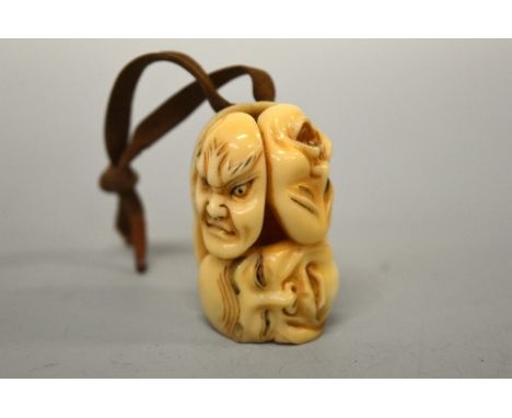 AN IVORY NETSUKE, late 19th Century, carved as four conjoined masks, signed to the base