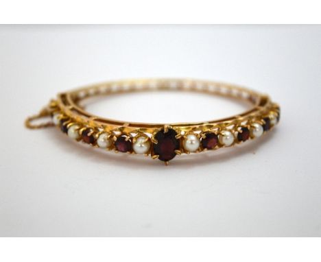 A 9CT GOLD GARNET AND PEARL BRACELET, with central oval shape garnet with alternating pearls and garnets to the twisted scrol