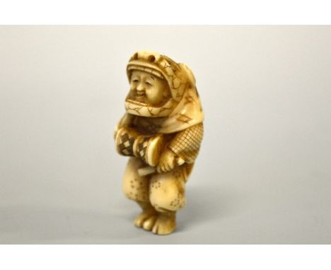 A JAPANESE IVORY NETSUKE, figurine dressed, in a Shi Shi dog mask banging a drum