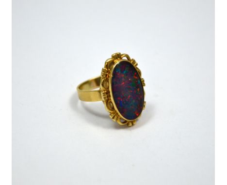 AN OPAL TRIPLET RING, of oval shape within a fancy scalloped border to the plain band, stamped 9ct, ring size Q 1/2