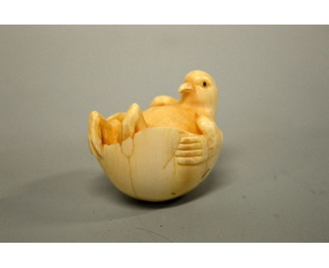 A JAPANESE IVORY NETSUKE, carved in the form of a bird relaxing in an egg, signed to base