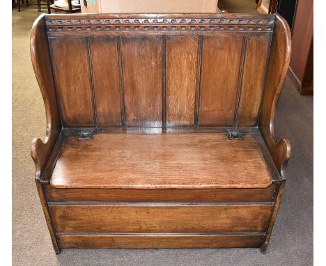 A Titchmarsh &amp; Goodwin Oak Settle, chip carved, with panelled backrest and hinged seat revealing a compartment below, 92c