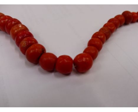 A STRING OF VINTAGE GRADUATED CORAL BEADS, CARVED CORAL EAR CLIPS, AND TWO COSTUME BRACELET. 