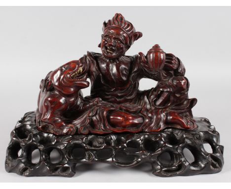 A GOOD CHINESE CARVED WOOD FIGURE of a man with a teapot, tiger standing on a pierced stand. 16ins wide.