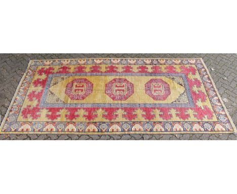 A TURKISH LONG CARPET, beige ground with three large geometric motifs to the central panel within a similarly decorated borde