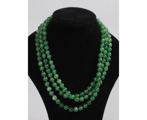 A LONG GREEN JADE NECKLACE.