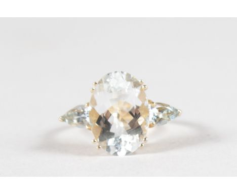 A 14CT YELLOW GOLD RING set with a large AQUAMARINE flanked by two pear shaped stones.