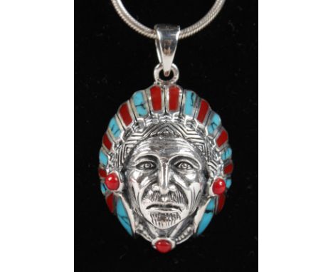 A SILVER, CORAL AND TURQUOISE SET INDIAN "CHIEF" PENDANT on a silver chain.