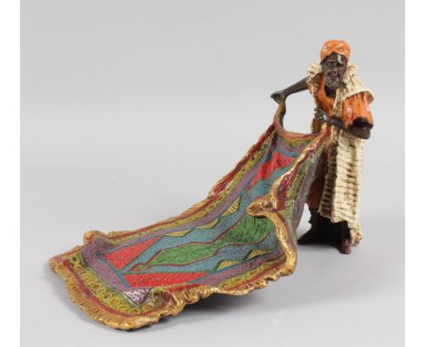 A LARGE PAINTED COLD CAST GROUP OF AN ARAB MAN SHOWING A CARPET. 10ins long, 6ins high.