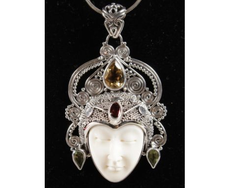 AN ART NOUVEAU STYLE CITRINE, GARNET AND PERIDOT CARVED FACE PENDANT AND CHAIN.
