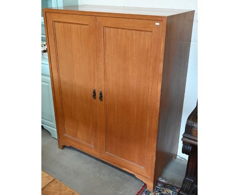 A teak hall/storage cupboard with two panelled doors enclosing wooden shelves, raised on bracket feet, 107 cm wide x 54 cm de