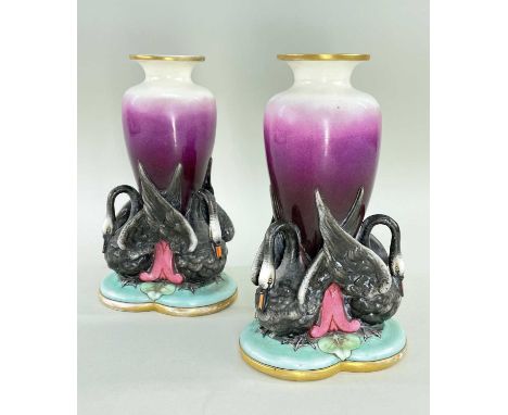 RARE PAIR OF WORCESTER PORCELAIN SWAN VASES, the graduated puce ovoid vessels supported by three black swans with upheld wing