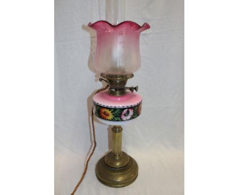 A late Victorian brass oil lamp with pink tinted opaque glass reservoir and cranberry tinted glass shade (converted to electr