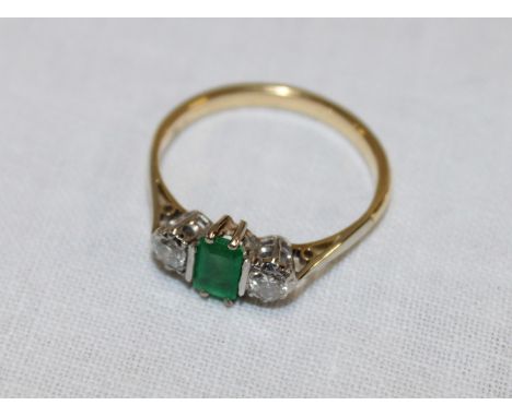 An 18ct gold Art Deco-style engagement ring set a central emerald flanked by two diamonds (2.7g)