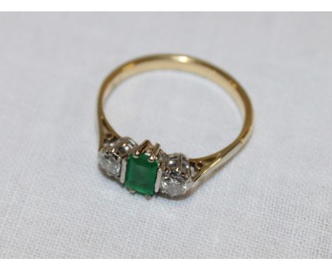 An 18ct gold Art Deco-style engagement ring set a central emerald flanked by two diamonds (2.7g)