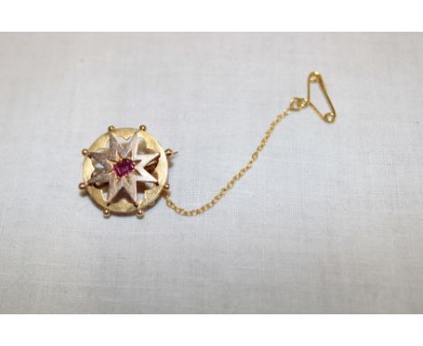 A gold circular star-shaped brooch set a central ruby (3.1g)