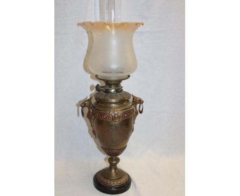 A brass pedestal oil lamp with detachable font and amber tinted opaque glass shade