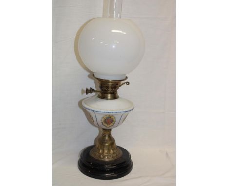 An Edwardian brass oil lamp with floral opaque glass reservoir and spherical shade