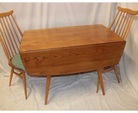 An Ercol pale elm drop-leaf dining table on square tapered legs together with a pair of spindle-back Ercol pale elm dining ch