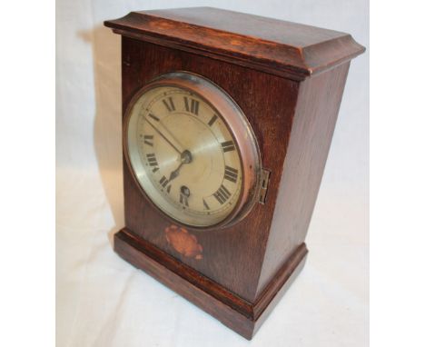 An Edwardian mantel clock with silvered circular dial in inlaid oak rectangular case