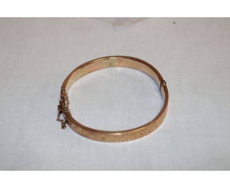 A 9ct gold oval bangle with engraved decoration (8.9g)