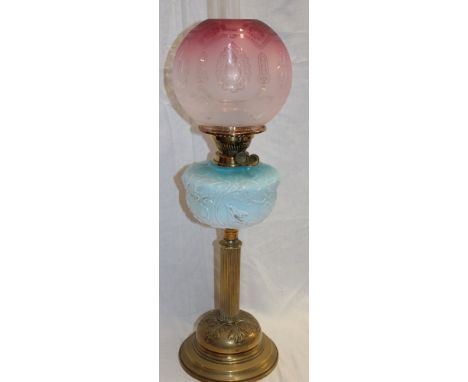 A Victorian brass oil lamp with column stem, blue tinted glass reservoir and cranberry tinted glass circular shade