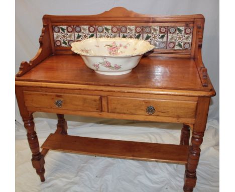 A Victorian polished pine wash-stand with two drawers in the frieze and ceramic tiled back on turned legs 42" long together w