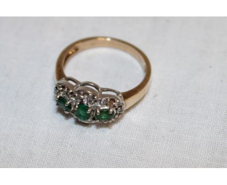 A 9ct gold dress ring set three emerald-style stones surrounded by diamonds (3.5g)