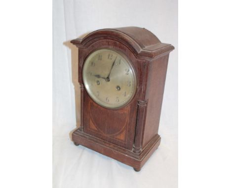 A German mantel clock with silvered circular dial in oak arched case