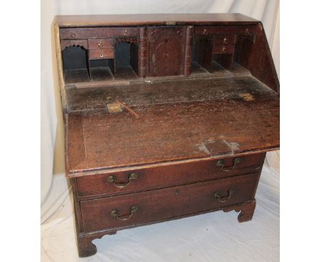 A 19th century oak bureau with numerous pigeon holes and drawers enclosed by a fall front above four long graduated drawers w