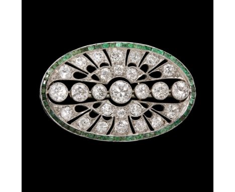 An early 20th century diamond and emerald set brooch  of oval outline, millegrain set with a central row of seven graduated o